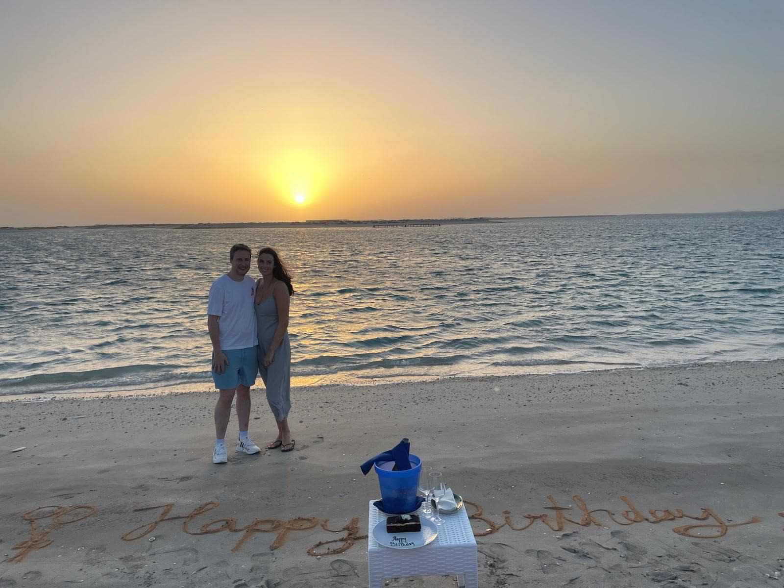 Sunset beach with Happy Birthday written in sand