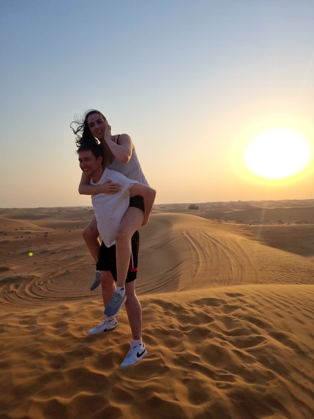 Piggyback on a desert dune at sunset