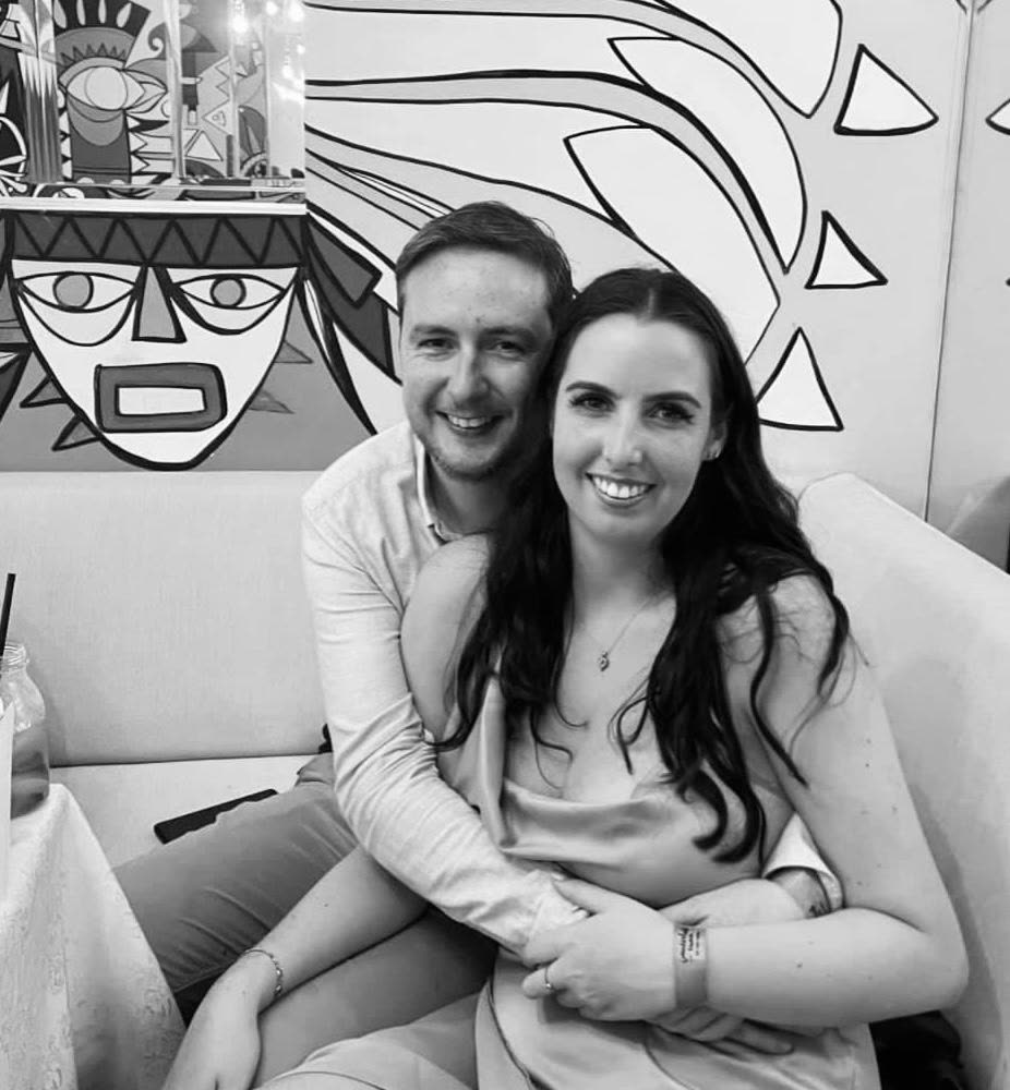 A black and white photo of the two of them cuddled up in front of a mural