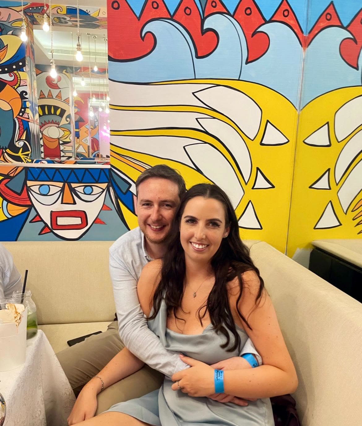 Cuddled in a booth before a bright mural