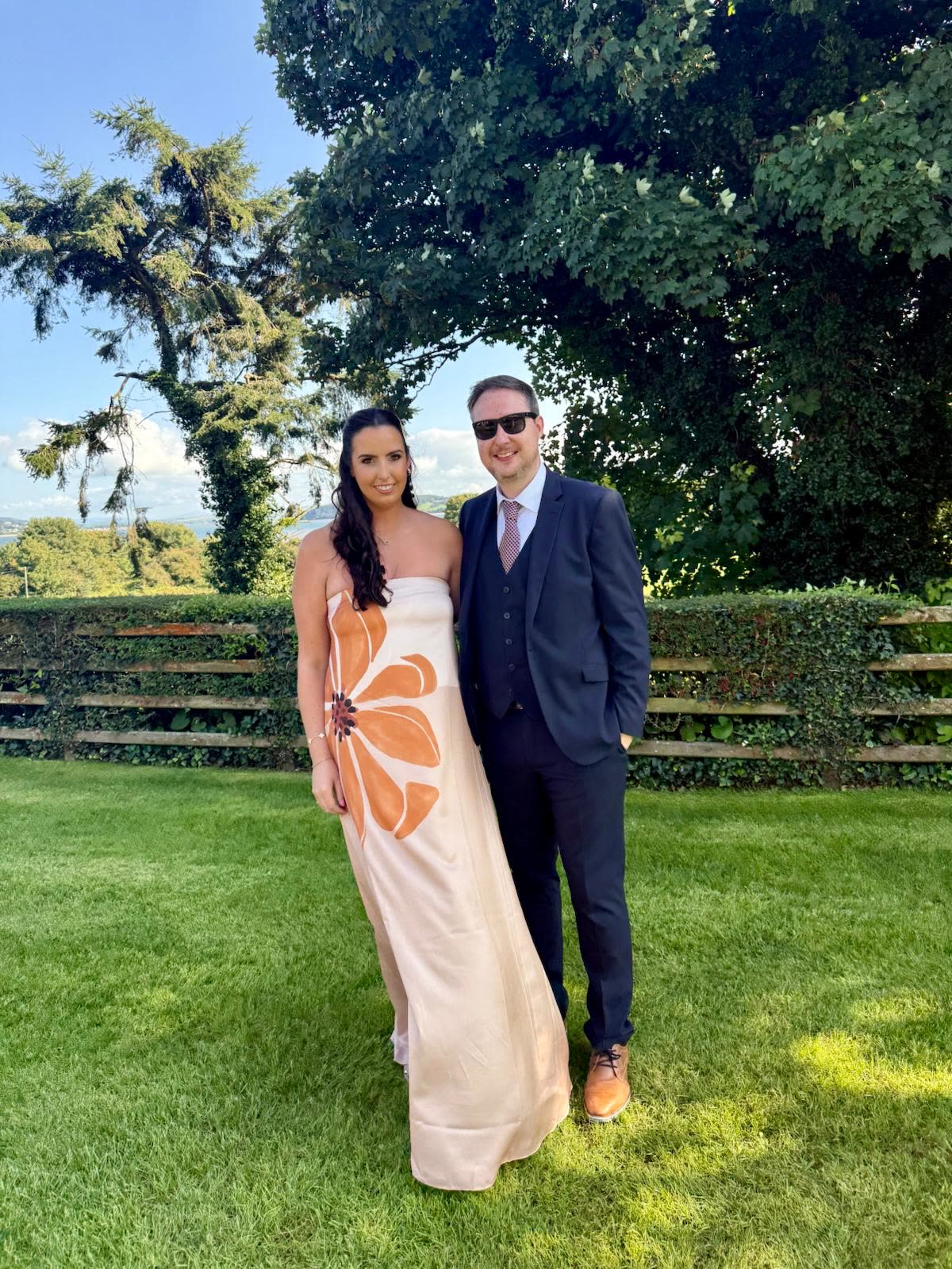 Orlaith and Niall dressed up on a garden lawn, trees behind them
